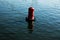 Floating red navigational buoy on blue water of Dnipro River.