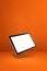 Floating tablet pc computer isolated on orange. Vertical background
