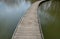 Floating walkway made of wood planks. narrow curved leads above the lake water. has no railings. more design sidewalk made of indi