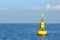 Floating yellow navigational buoy on blue sea