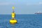 Floating yellow navigational buoy on blue sea