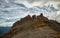 flock of birds flies over the sharp rocks in the sunset light against the backdrop of clouds. Caucasus Mountains, Arkhyz