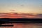 Flock of birds flying over lake in sun direction during at sunset. Beautiful colorful scenic dusk with dramatic sky and seagulls o