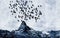 A flock of birds traveling together over a blue mountain.