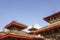 Flock of gray pigeons sitting on the red roofs of ancient Asian temples against a clean blue sky