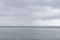 A flock of migratory birds flying wedge over the sea. Cloudy weather. Selective focus.