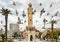 Flock of pigeons flying around the Izmir Clock Tower in Izmir, Turkey.