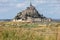 A flock of sheep grazing on the salt meadows close to the Mont Saint-Michel tidal island under a summer blue sky. Le Mont Saint Mi