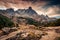 Flock of sheep walking through rock hill on pasture with Main De Crepin peak in Claree valley on autumn