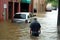 Flooded car and a man on the street of the city. Disaster Motor Vehicle Insurance Claim Themed. Generative AI.