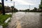 Flooded city street after thunderstorm. The road and the sidewalk are covered with water after the massive rain. The flood makes