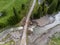 Flooded mountain river flowing under the forest road aerial drone view