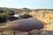 Flooded quarry with red water and dried hills with rare vegetation.