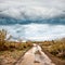 Flooded road in prairie and dramatic sky