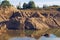 Flooded sand quarry. Cracked drought clay piles during the dry season. Bright yellow or orange texture sand color land. Stock