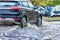 Flooding in the city after the rain. The car drives through a puddle in the pouring rain. Splashes of water from under the wheels