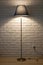 Floor lamp on the background of a textured wall of white brick. wooden shelf. texture, background, lighting, design in the interio
