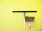 Floor squeegee rubber blade and sweeping broom beside the yellow wall