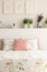 Floral bedding and pastel pink cushion on double bed in real photo of white bedroom interior with lavender, posters and decor