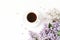 Floral composition made of beautiful purple lilac, syringa flowers on white wooden background with cup of coffee