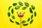 Floral composition made of green ruskus leaves and golden sequin crown on yellow background. Creative layout , top view