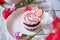 Floral cupcake among flowers decoration. Escapism concept of dreamy french desserts. Spring food background