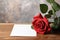 Floral simplicity Red rose with white paper on rustic tabletop