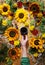 Floral summer background. A mug of coffee in a woman`s hand on a wooden background with sunflowers and wildflowers