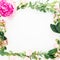 Floral wreath frame of pink peony and roses flowers, hypericum and eucalyptus branches on white background. Flat lay, top view