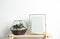 Florarium with succulent plants and photo frame on table near white wall. Home decor