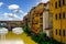 Florence Italy Houses Ponte Vecchio Bridge along Arno River Under bright Blue Sky