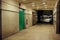 Florescent lit underpass with a green service door leading into darkness