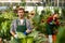 Floriculturist standing among green houseplants with watering can