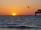 Florida sunset with seagulls and silhouette of a pier with people fishing and enjoying the sunset