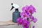 A florist girl holds a bottle with water sprayer near a purple orchid.