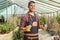 Florist in a greenhouse holding a small evergreen tree