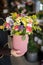 Florist holding a vase with beautiful flower arrangement of pink roses, lilac asters, white chrysanthemums and other plants in the