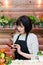 Florist holds a smartphone in his hand on the background of a wooden wall with flowers