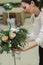 Florist make winter wedding bouquet composition on stand indoors