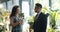 Florist pretty girl selling exotic plant to middle-aged man in flower store