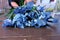 Florist woman creates bouquet from blue iris flowers on table for sale in shop.