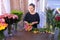 Florist woman makes bouquet from small colourful roses works in flower shop.