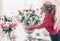 Florist women in red shirt, make beautiful big festive event classical bouquet with roses and other flowers