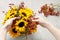 Florist at work: how to make floral arrangement with sunflowers and wild rose rosa canina twigs