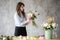 Florist at work: pretty young woman making fashion modern bouquet of different flowers