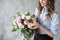 Florist at work: pretty young woman making fashion modern bouquet of different flowers