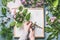 Florist at work space . Female hands making flowers arrangement with green branches and pink flowers