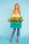 Floristics, holidays and people concept - Stylish blond young woman holding box of yellow tulips on blue background