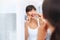 Flossing away. Shot of a cheerful attractive young woman flossing her teeth while looking at her reflexion in a mirror