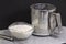 Flour in a bowl next to a mechanical sieve on dark background